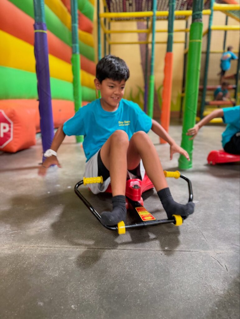 Camper riding a scooter cart across the arena floor