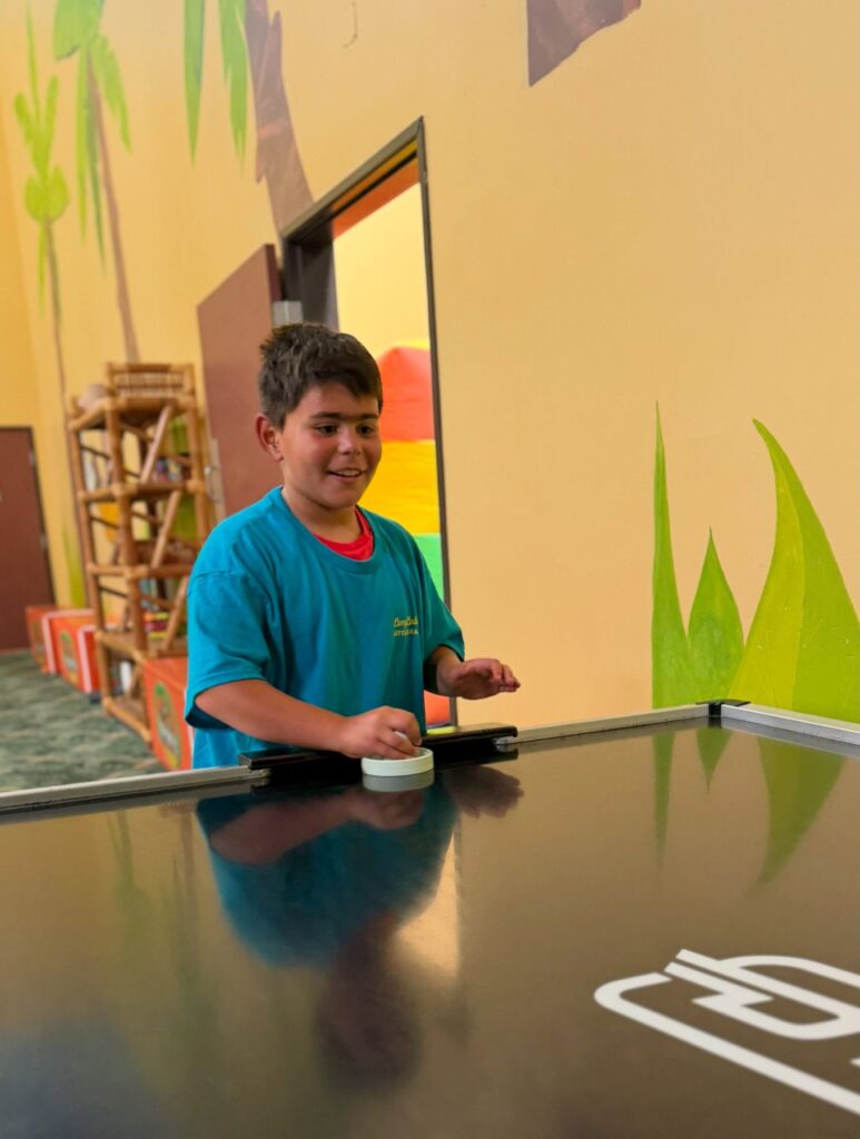 Camper playing air hockey during a camp field trip